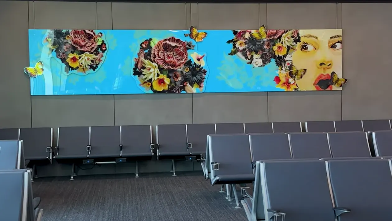 Colorful mural on a bright blue background featuring blooming flowers, butterflies, and a surprised woman’s face, blending realism with collage-like elements.