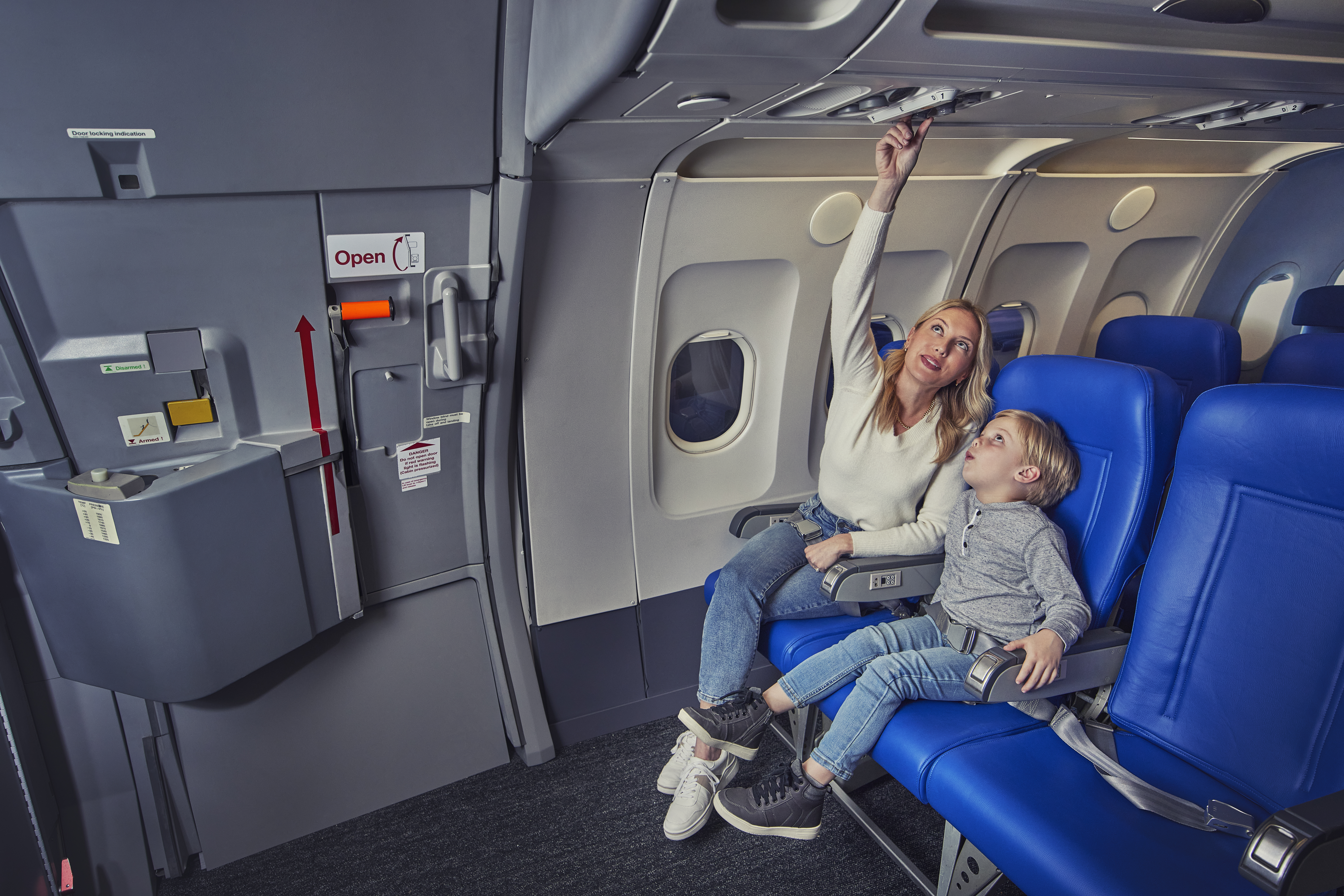 Travelers looking at the overhead lights on an airplane