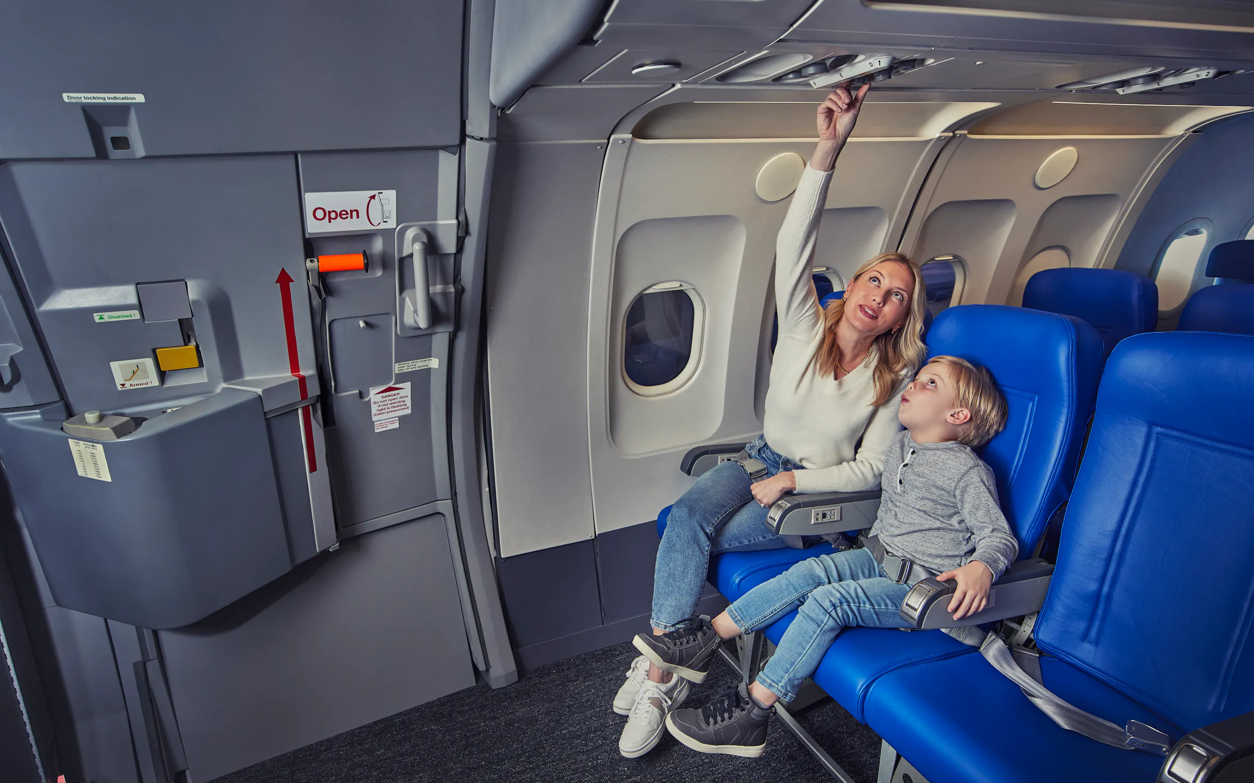 Travelers looking at the overhead lights on an airplane