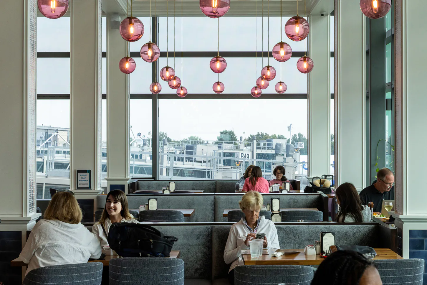 Travelers dining is a restaurant as they wait for their flight. 