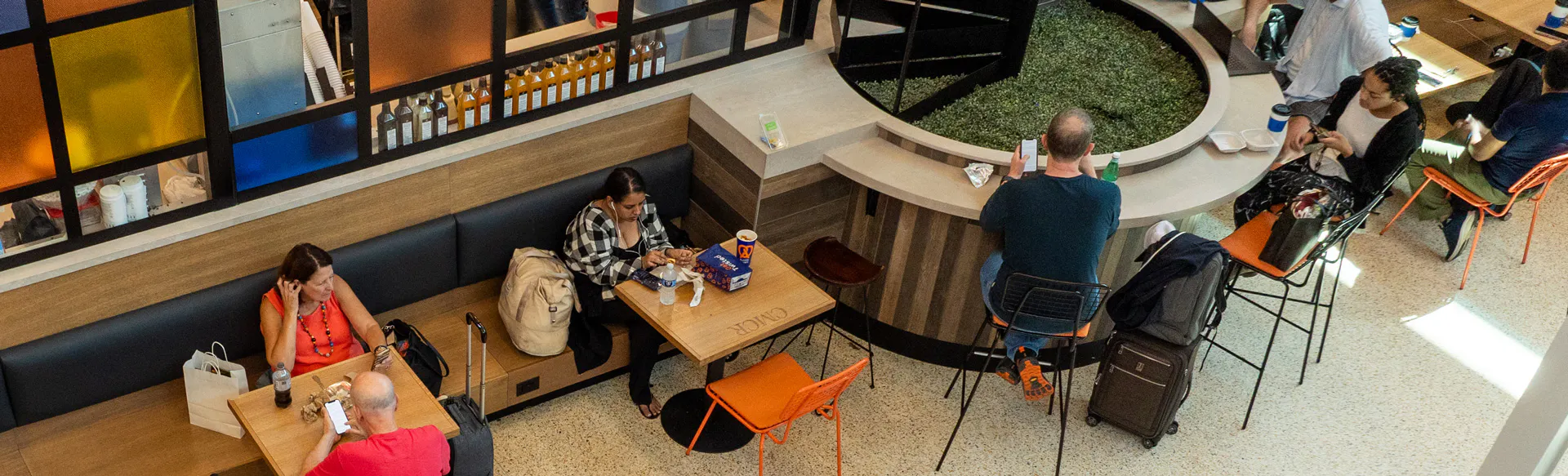 Travelers sit in a restaurant working and relaxing with coffees as they wait for their flights.