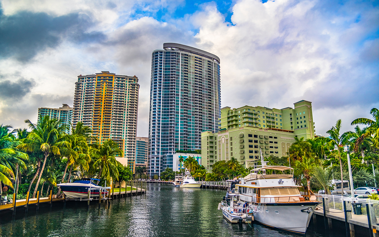 Photo of the canals and high-rise buildings in Ft. Lauderdale, Florida with palm trees and blue skies
