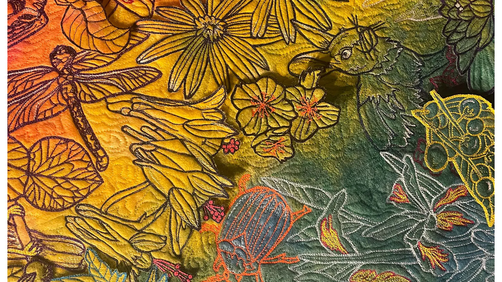 Close-up of a richly embroidered fabric artwork with vivid yellow, green, red, and orange hues, depicting layered flowers, insects, a bird, a beetle, and intricate stitched leaves.