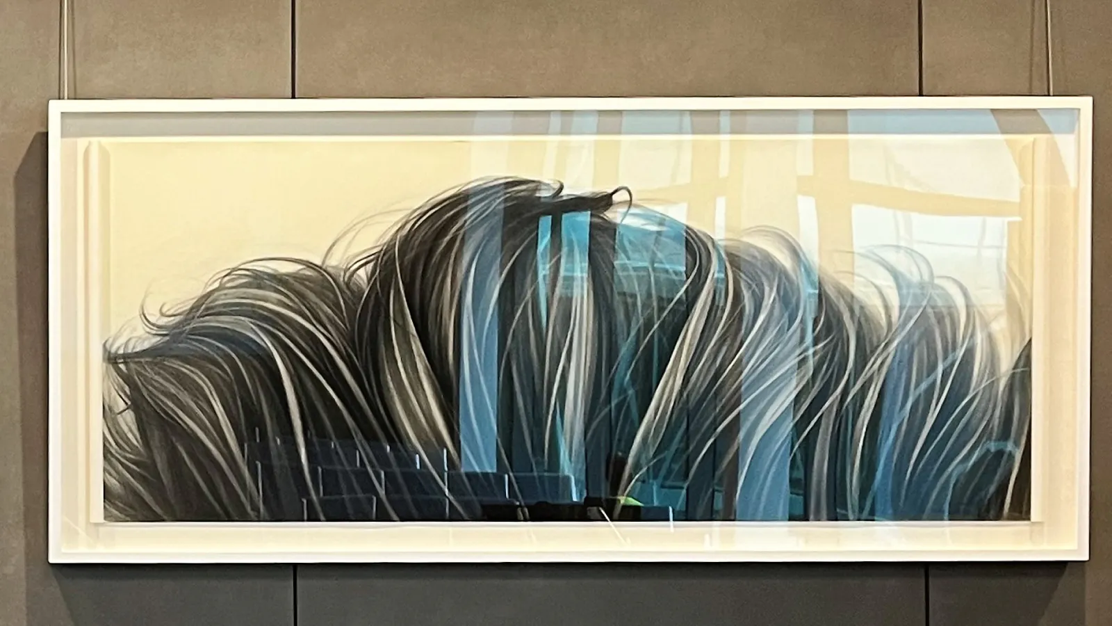 Framed painting of flowing, windswept grass in dynamic strokes of black, gray, and blue against a pale yellow background, suggesting motion and energy.
