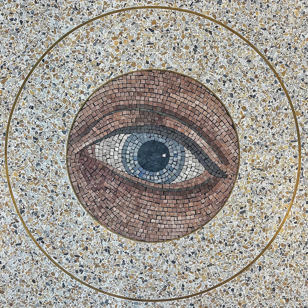 Floor mosaic featuring a realistic human eye rendered in shades of brown, gray, and blue, encircled by terrazzo with a brass ring.