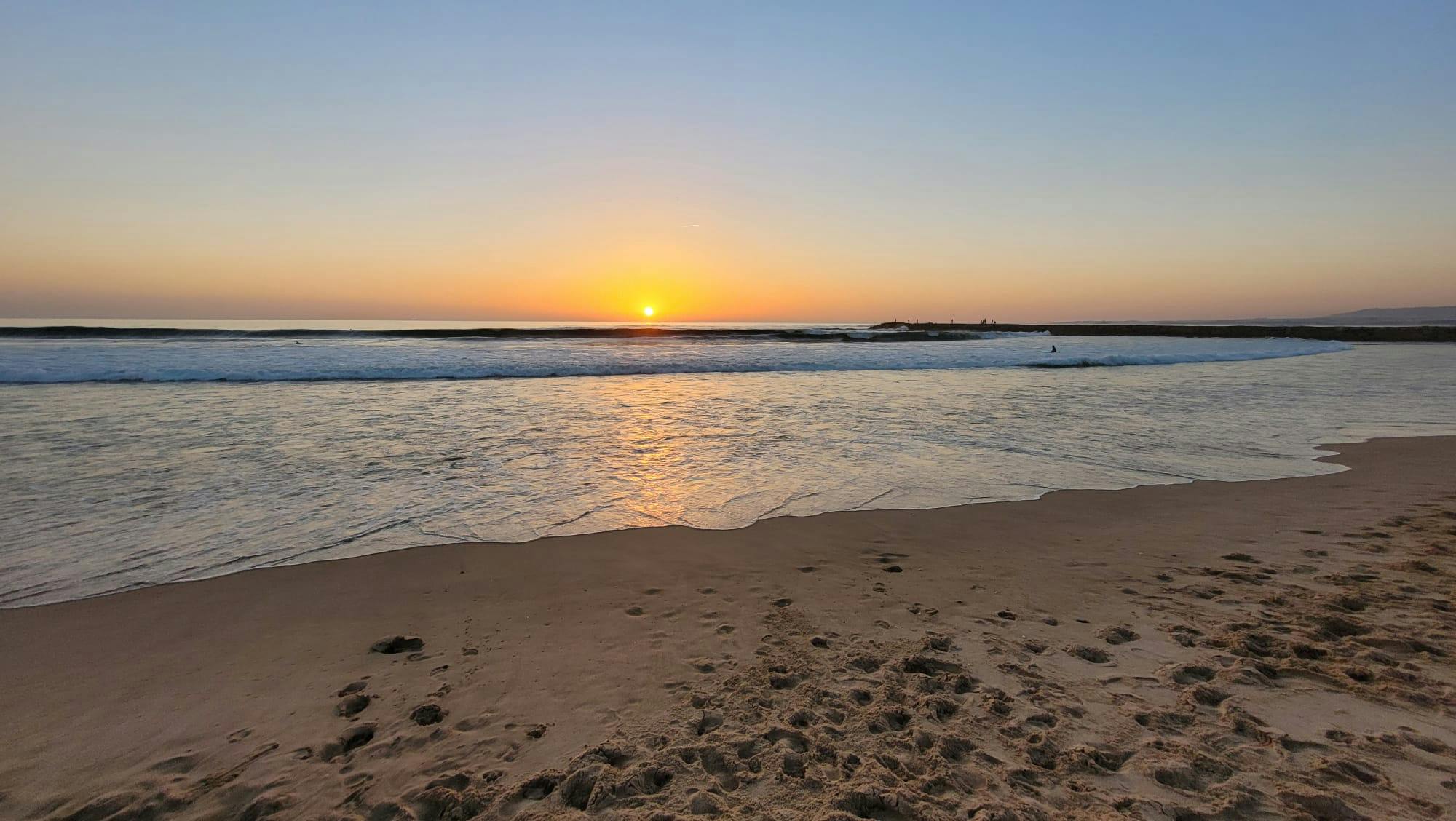 Caparica o zachodzie słońca: piaszczysta plaża, morze i zachodzące słońce
