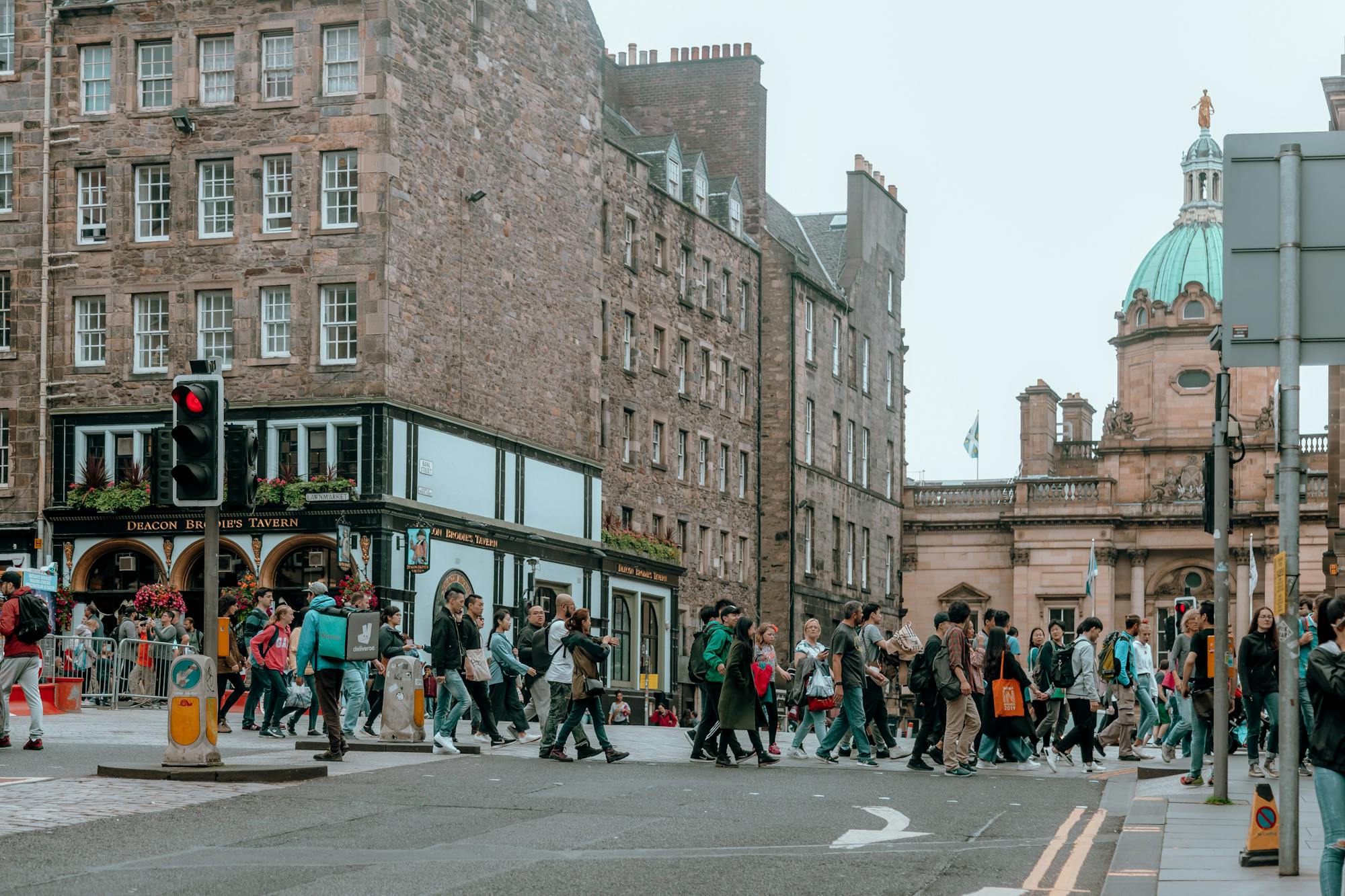 Straße in Edinburgh mit zahlreichen Menschen, welche gerade die Ampel überqueren  