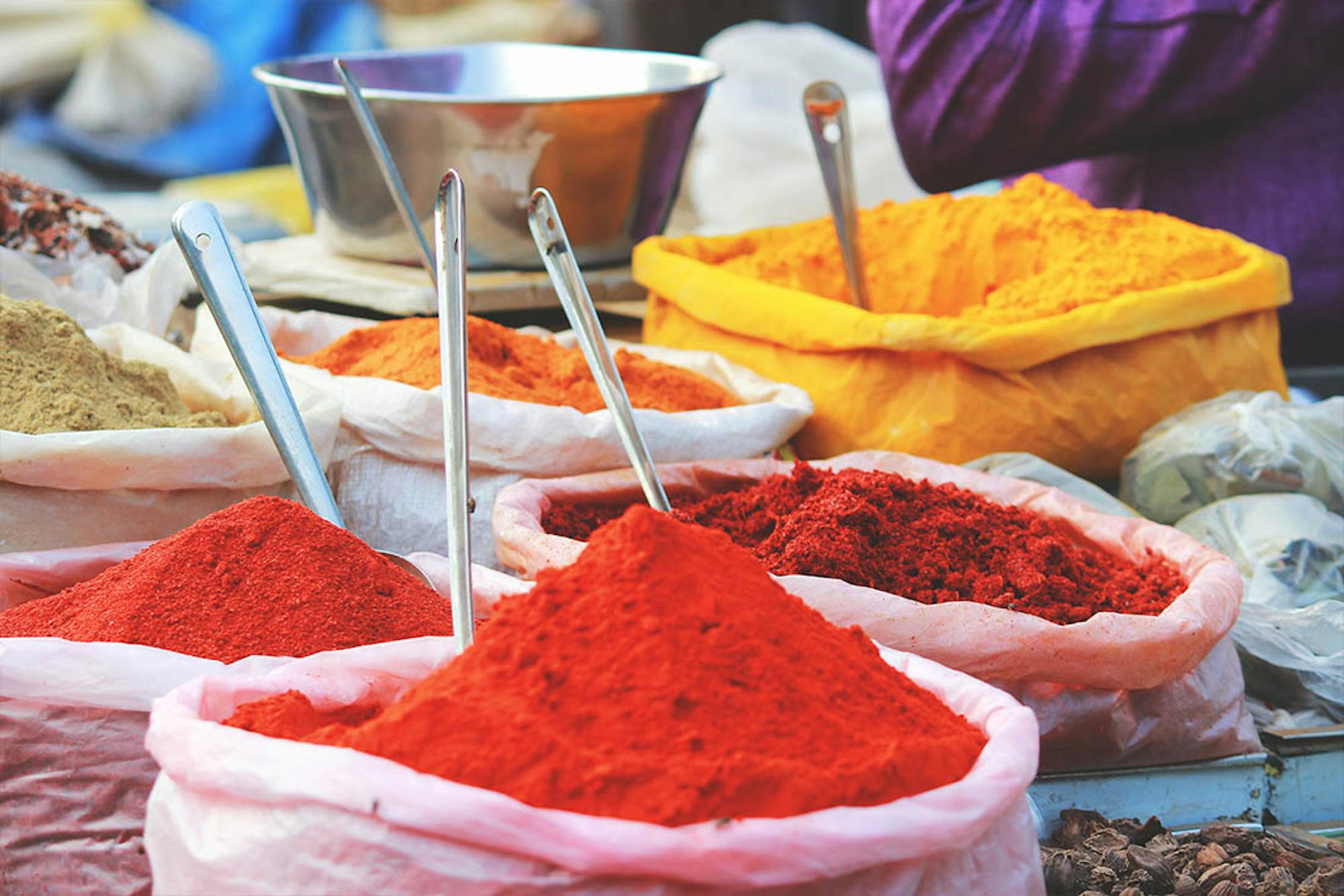 Różnorodność indyjskich przypraw jest ważona i sprzedawana przez sprzedawców na targu w dużych workach.