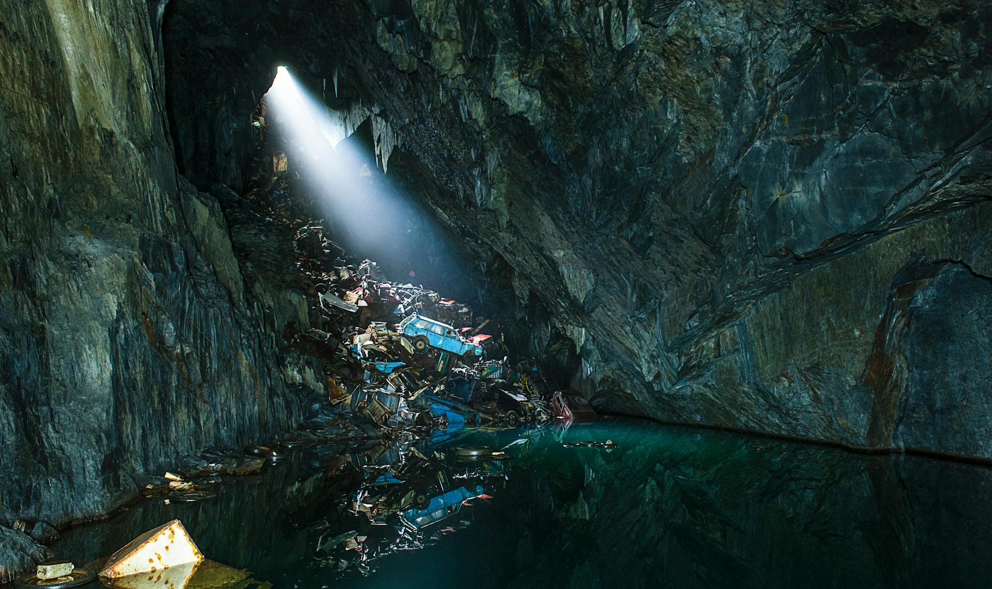 Z małej szczeliny do ciemnej jaskini wodnej wpada promień światła słonecznego.