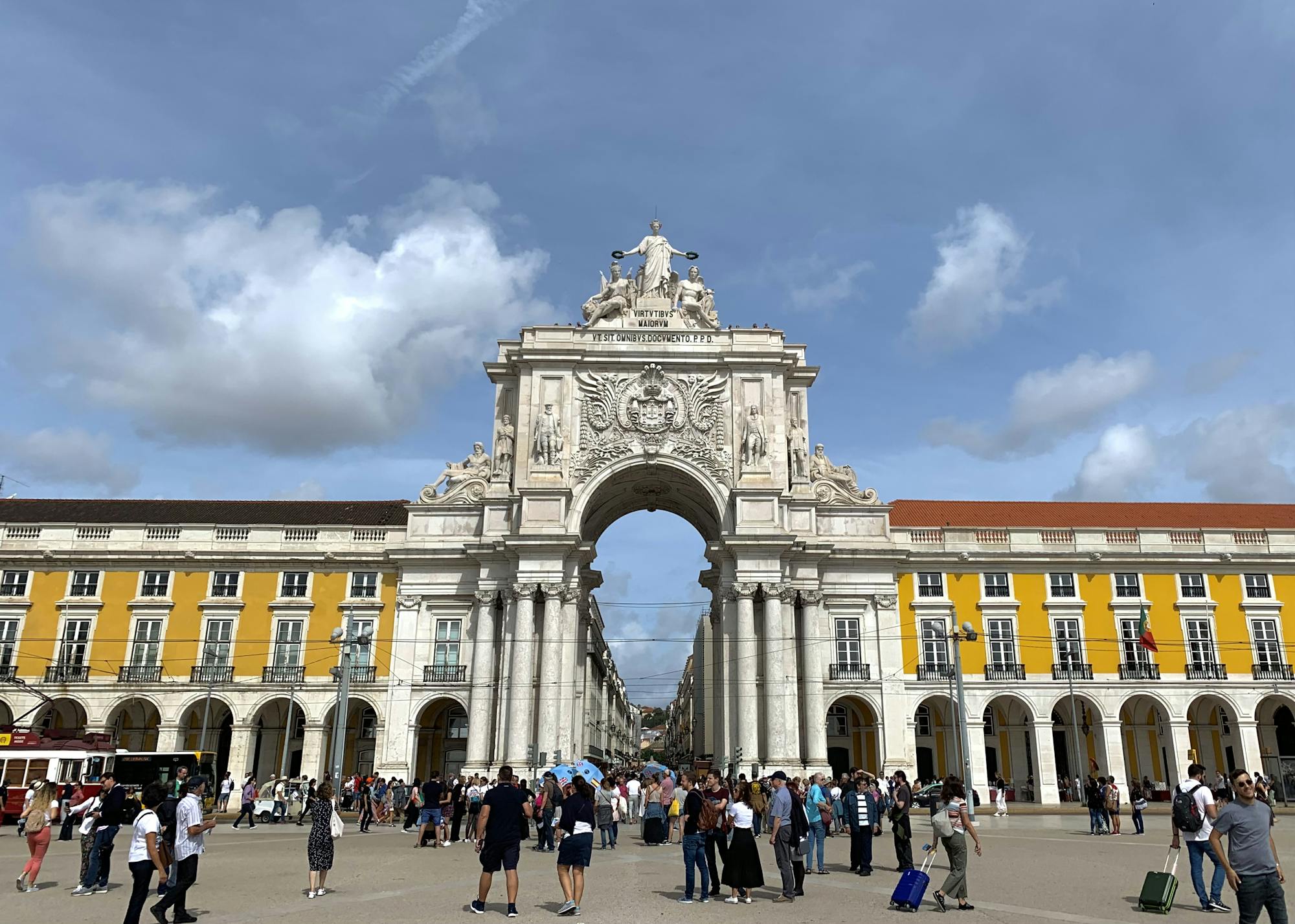 Wielu ludzi przechodzi przez Łuk Triumfalny, aby dotrzeć do ulic handlowych Lizbony.