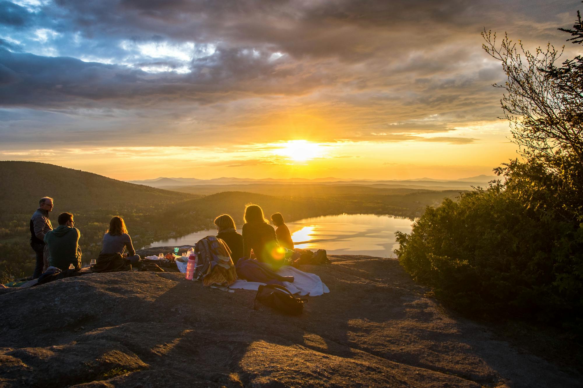 Sonnenuntergangs-Picknick auf dem Berg mit Ausblick auf die Berge und einen See 