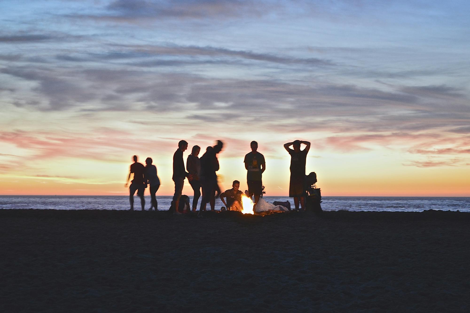Eine Freundesgruppe macht ein Lagerfeuer am Strand.