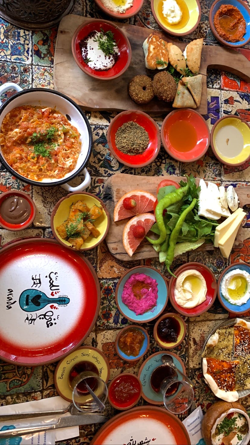 Ein Tisch, voll gedeckt mit vielen unterschiedlichen Aufstrichen, türkischem Tee, Brot und süßem Gebäck.  