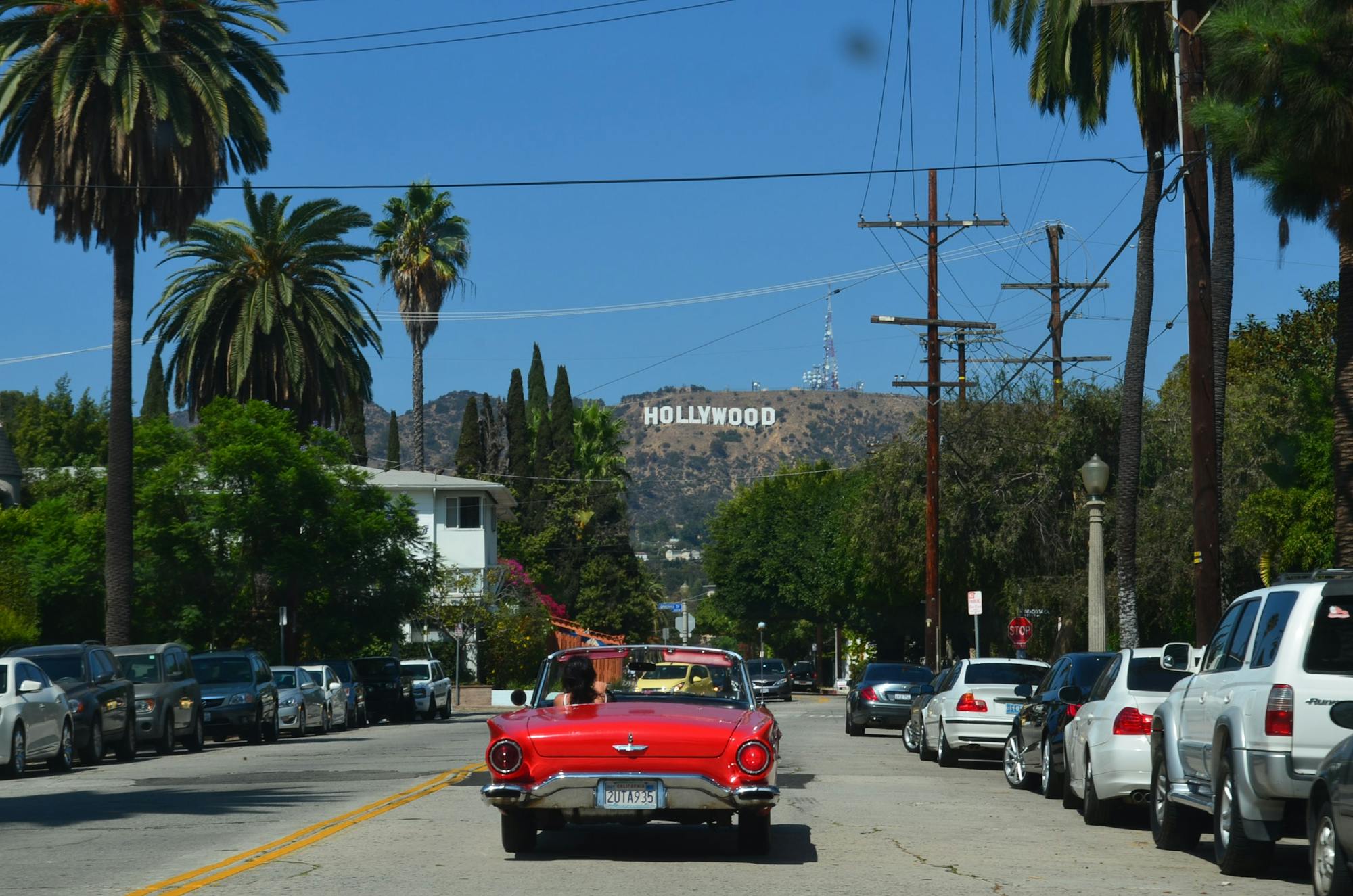 Kabriolet jedzie ulicą w L.A. w kierunku znaku Hollywood.