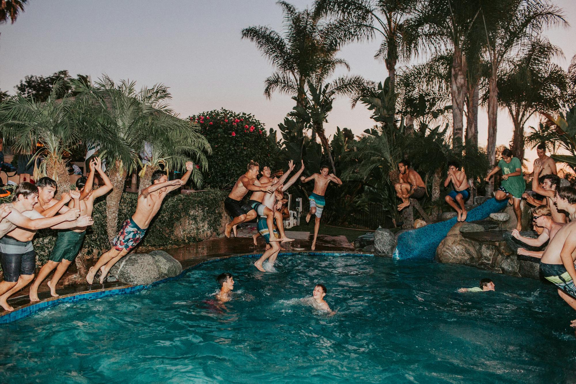 Pool-Party: Junge Leute feiern ausgelassen im Pool und springen ins Wasser. 
