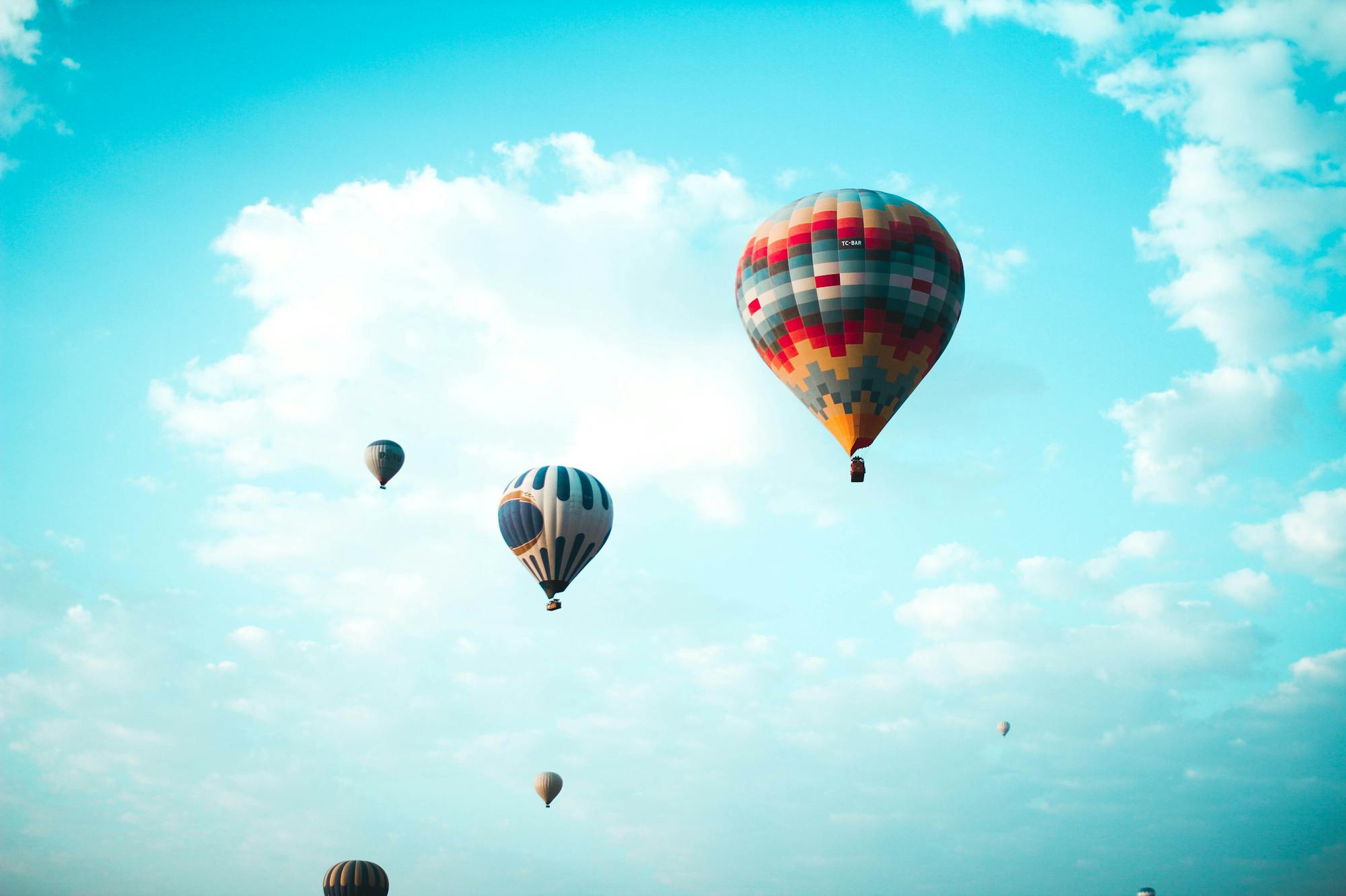 Wiele kolorowych balonów na gorące powietrze unosi się w błękitnym niebie.