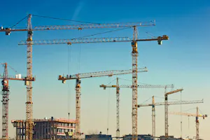 Viele Baukräne auf einer großen Baustelle vor wolkenlosem Himmel