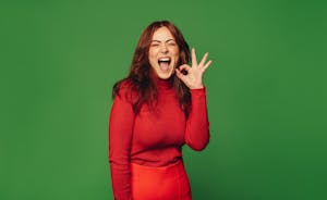 Fröhliche Frau macht das "OK"-Zeichen