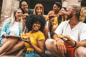 Fröhliche Freunde, die auf der Stadtstraße Pizza essen