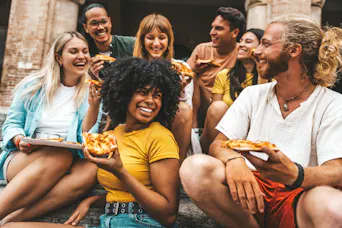 Fröhliche Freunde, die auf der Stadtstraße Pizza essen