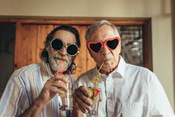Senior Männer mit lustigen Sonnenbrillen trinken Saft