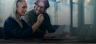 Geschäftsleute treffen sich im Büro und diskutieren über Dokumente. Geschäftsfrau mit einem Finanzbericht in der Hand sitzen mit männlichen Kollegen schauen sie und lächeln.