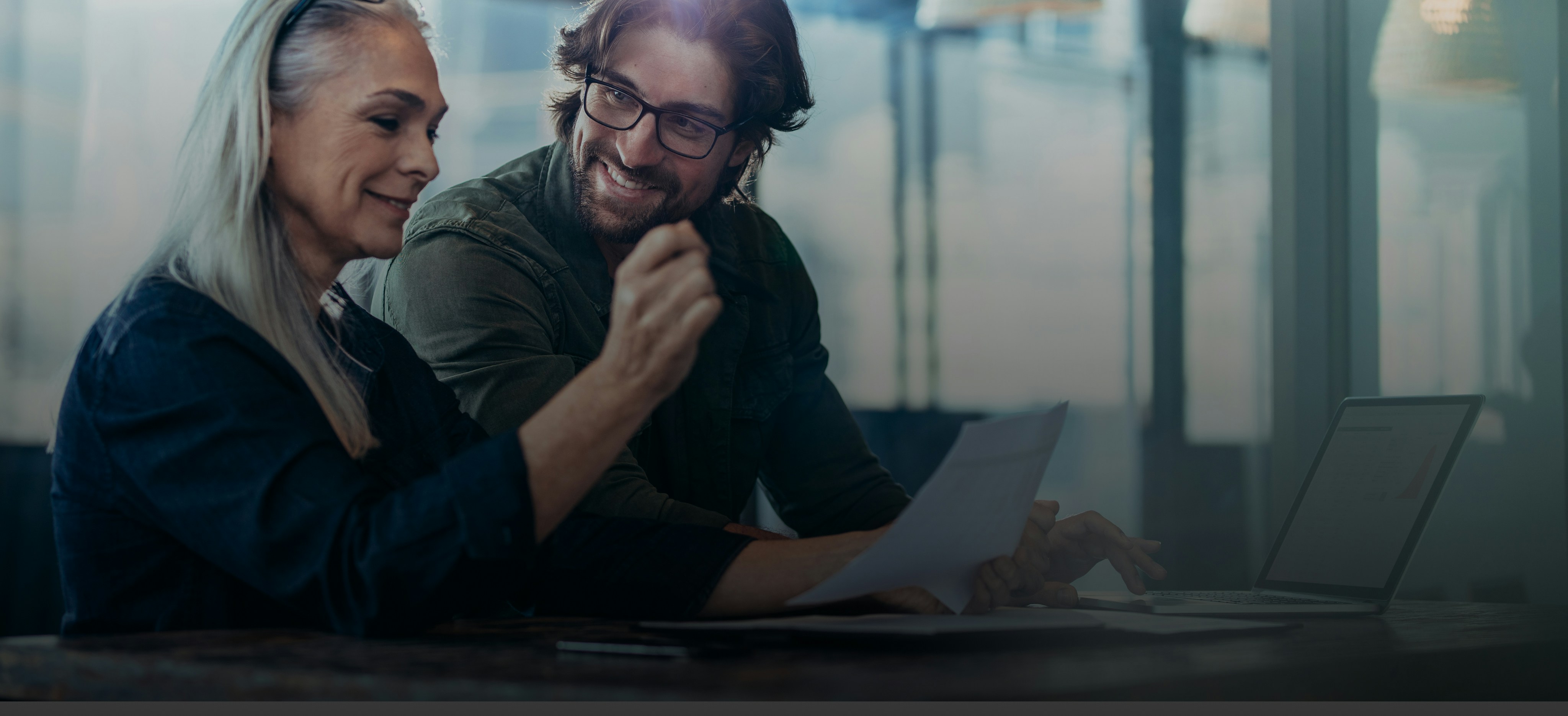 Geschäftsleute treffen sich im Büro und diskutieren über Dokumente. Geschäftsfrau mit einem Finanzbericht in der Hand sitzen mit männlichen Kollegen schauen sie und lächeln.