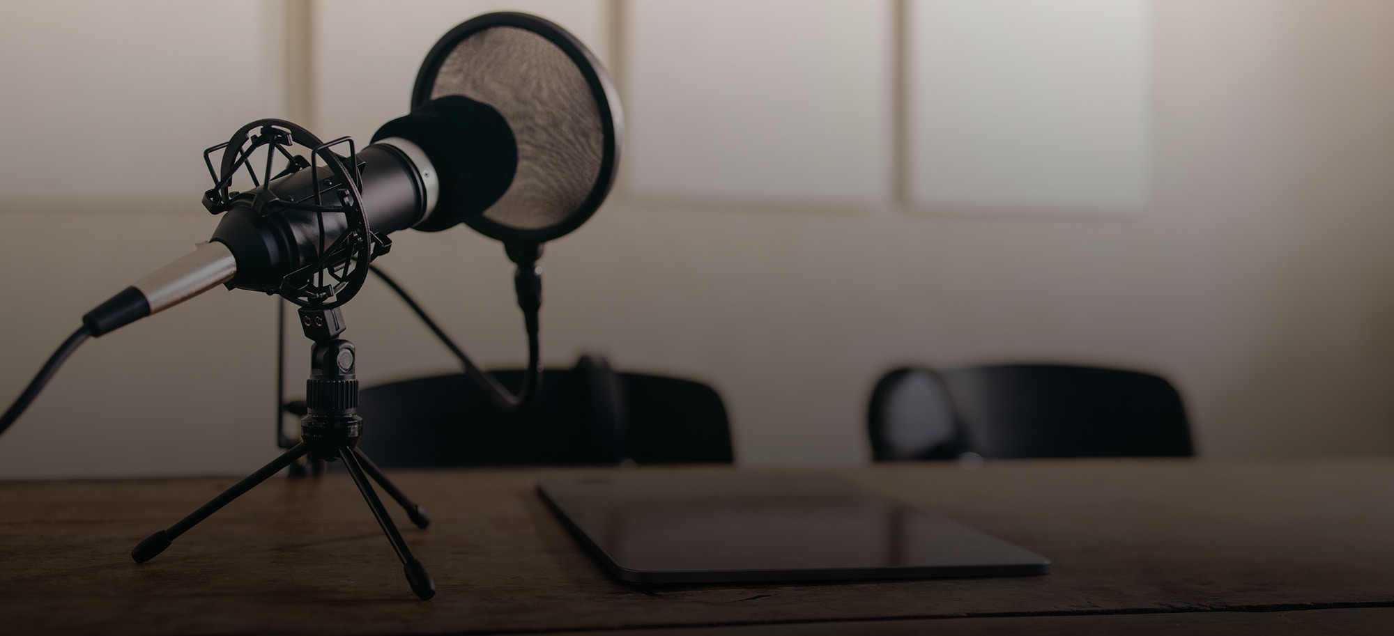 Stillleben eines Mikrofons mit einem Pop-Schild auf einem Tisch neben einer digitalen Tablette. Podcast-Recording-Gerät in einem Heimstudio.