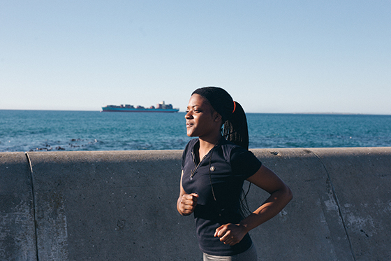 Woman in running kit running alongside the sea.
