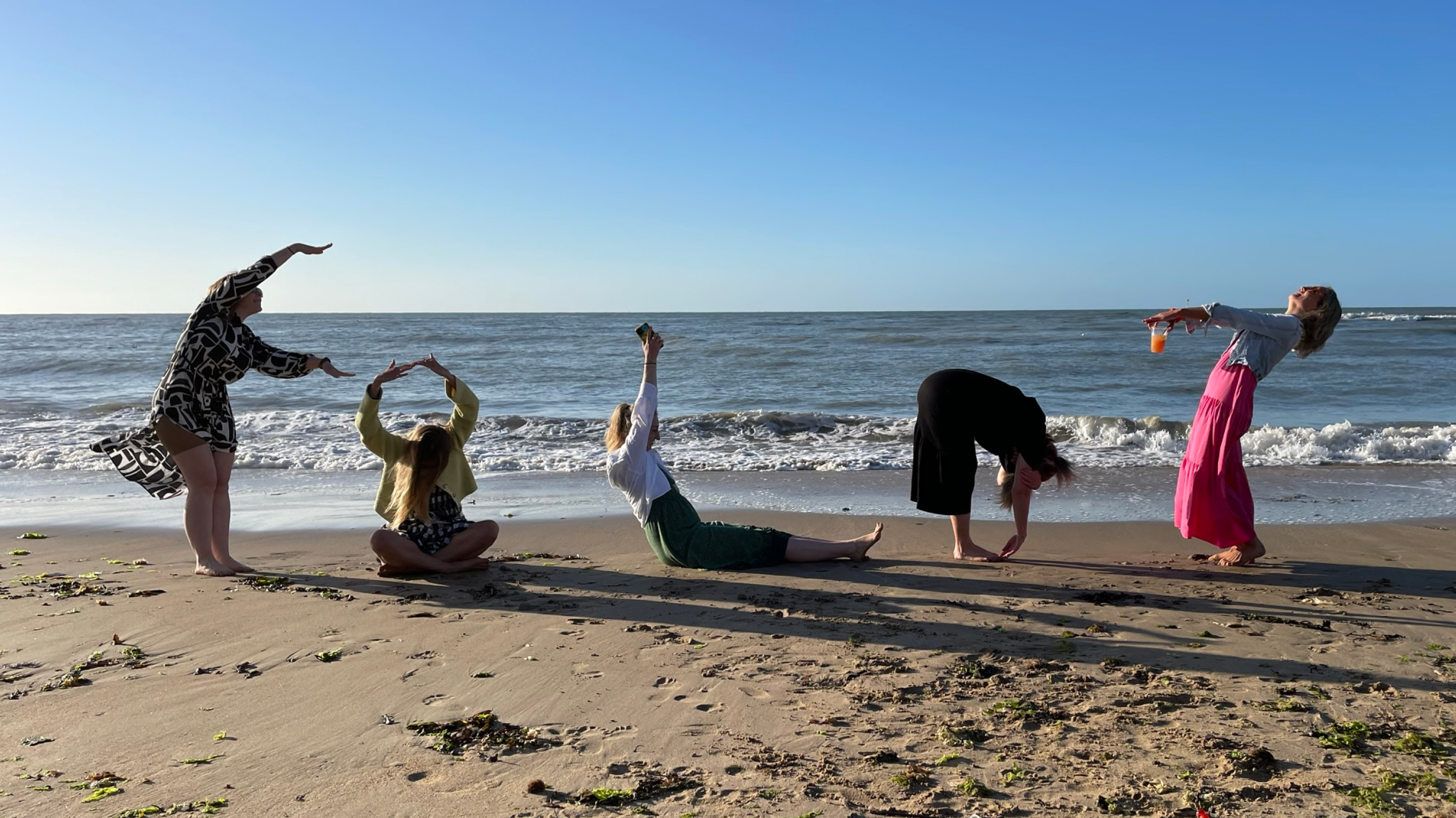 People on the beach spelling out Fold with their postures