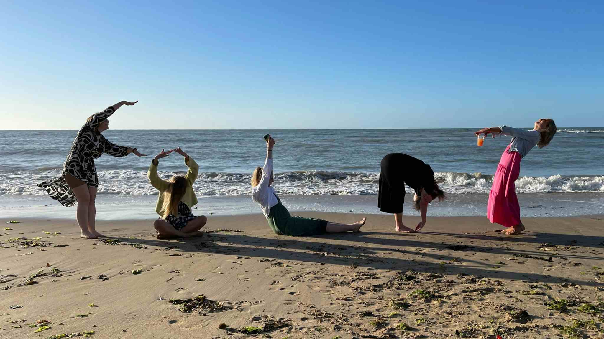 People on the beach spelling out Fold with their postures