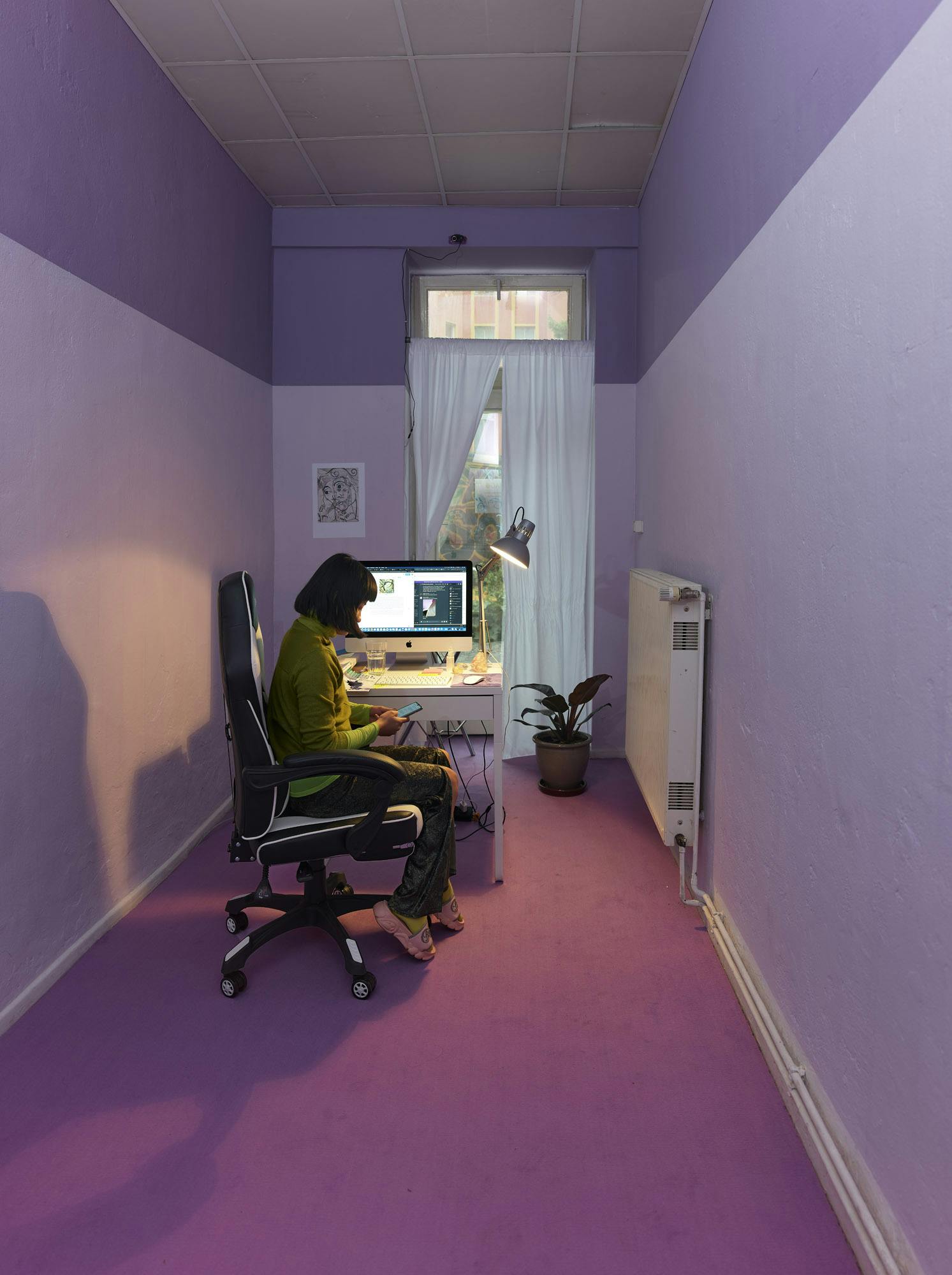 Eastyn sitting at their computer in a pink and lavender room.