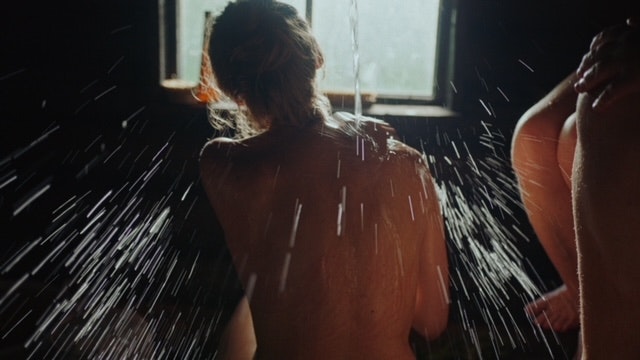 Back view of woman in a sauna with water being poured over her.