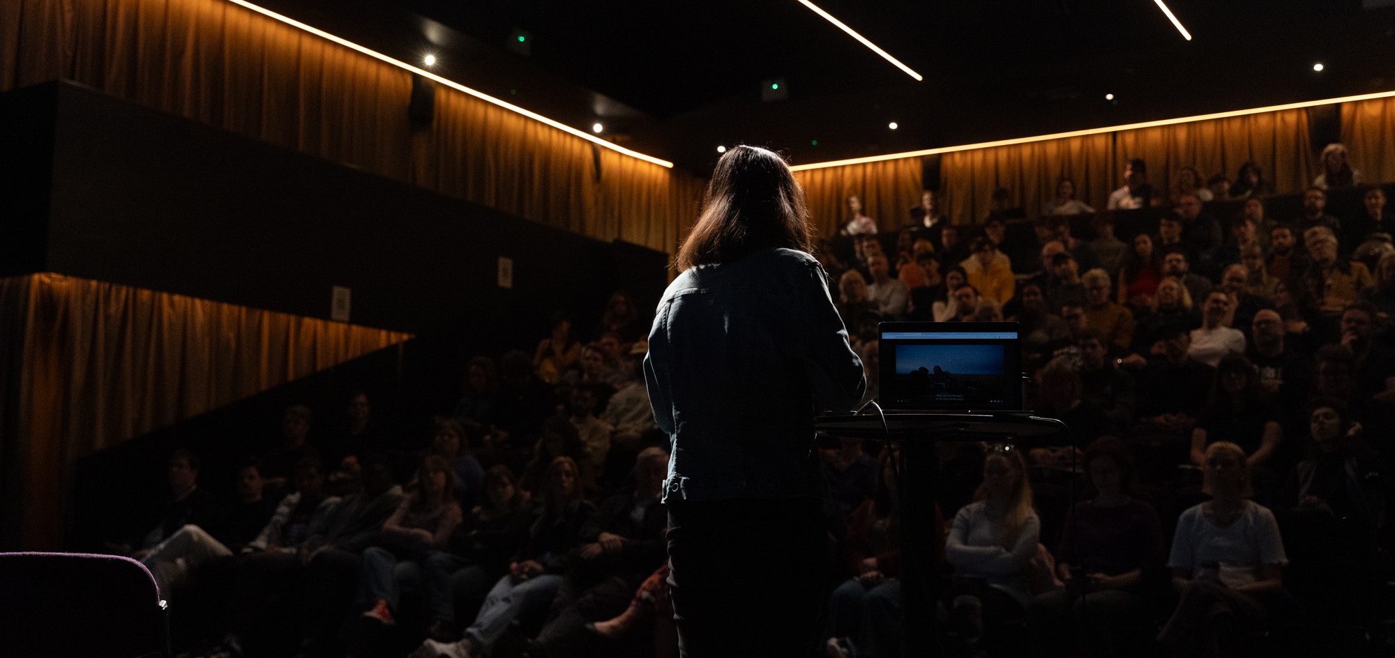A woman presents to a crowded auditorium
