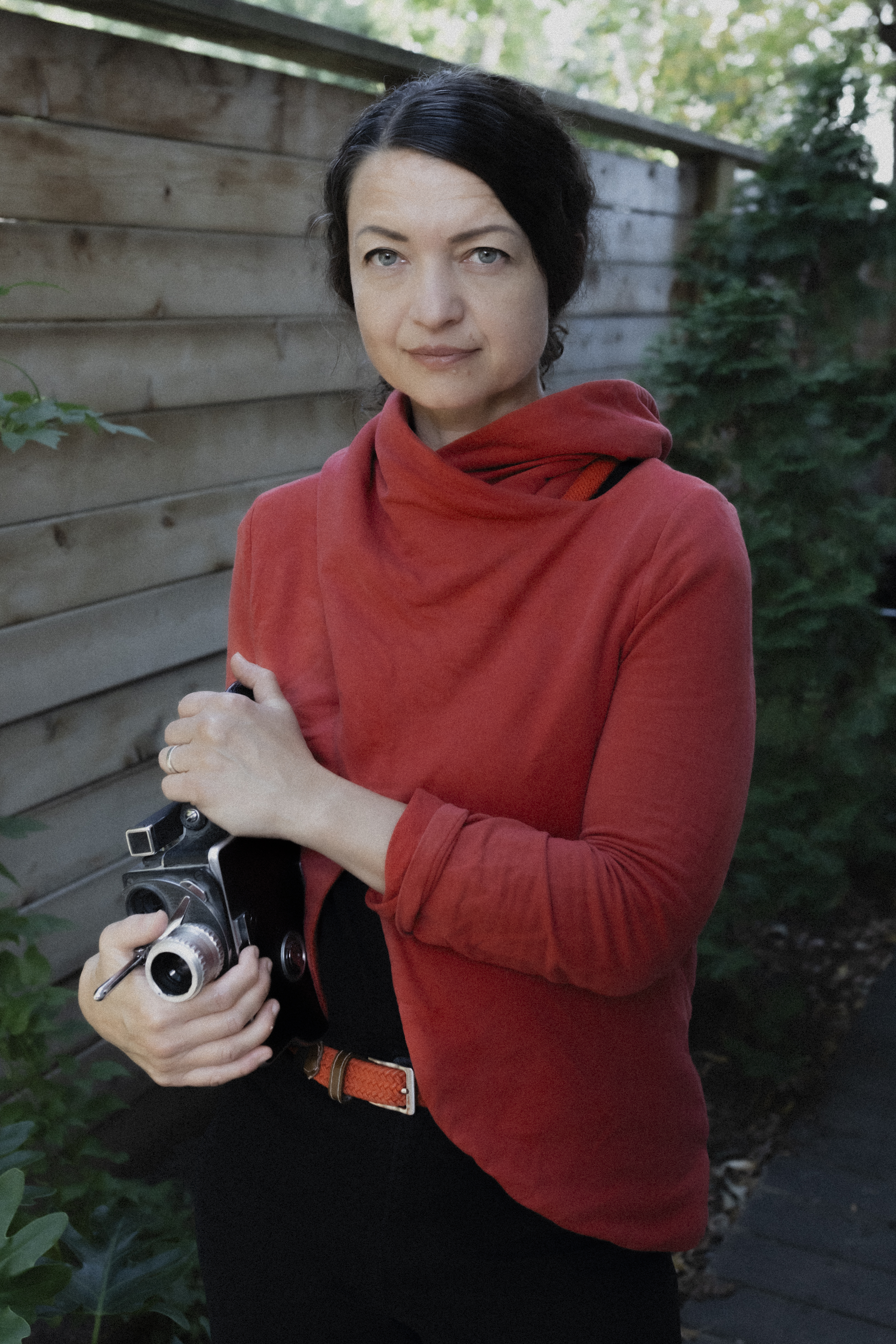 Woman looks into the camera holding a film camera