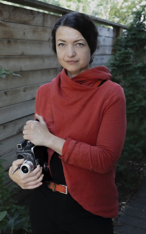 Woman looks into the camera holding a film camera