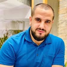 a man in a bright blue shirt looks to camera