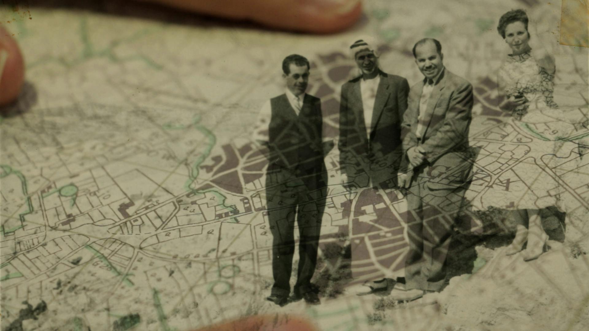 Old photograph of three people standing on a map
