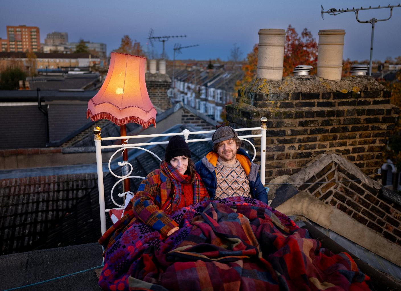 A man and a woman in bed on the roof of their house
