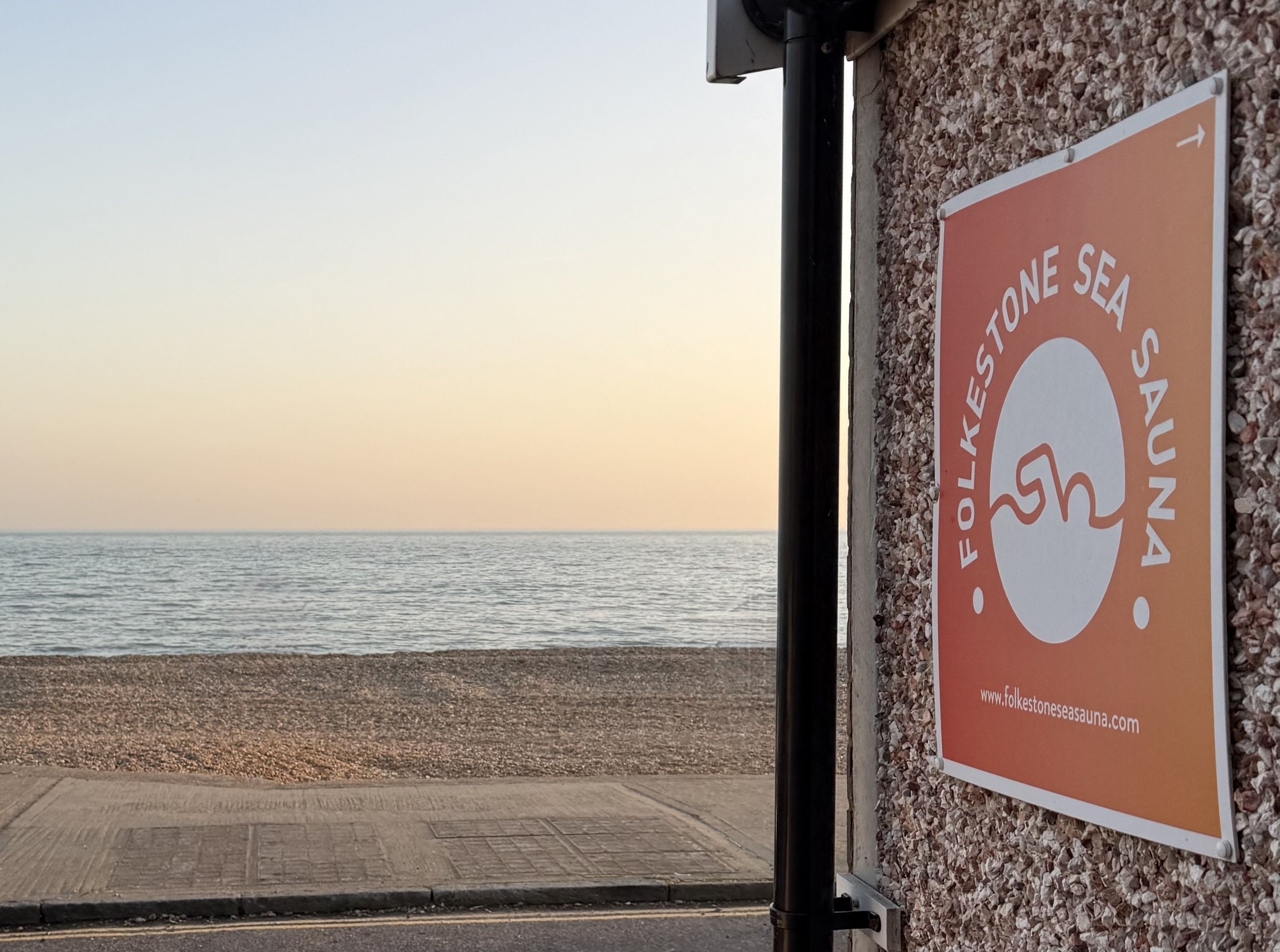 View over the sea at Sandgate with the Folkestone Sea Sauna sign in the foreground