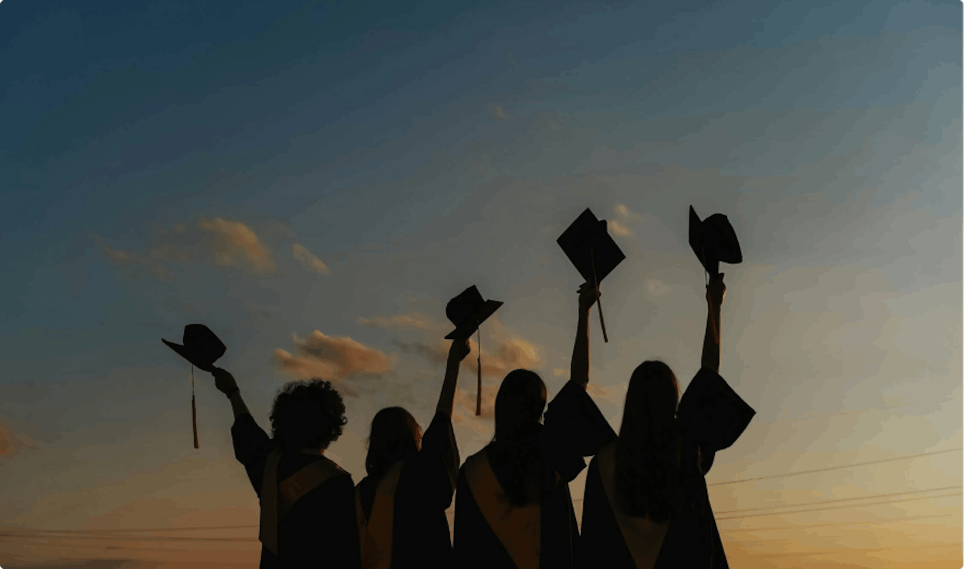 Fotografia di ragazze al tramonto che alzano i cappelli della laurea