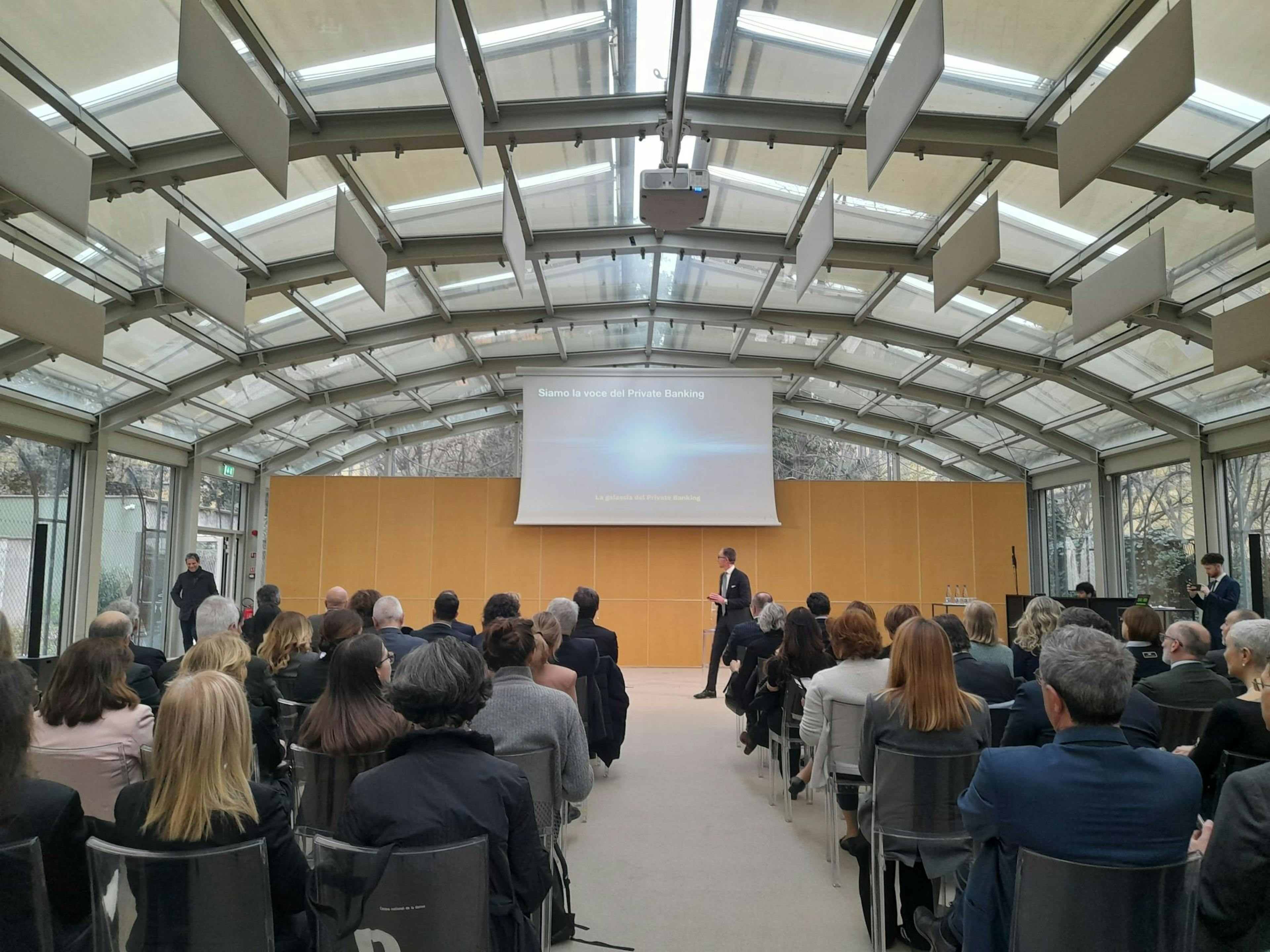 Sala con persone sedute guardano la presentazione su Private banking e filantropia