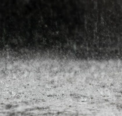 A black and white photo of rain falling on the ground