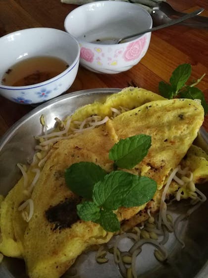 A plate of omelette fried with beansprouts, accompanied by a bowl of soup