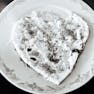 A plate of sourdough bread with white frosting, shaped like a heart.
