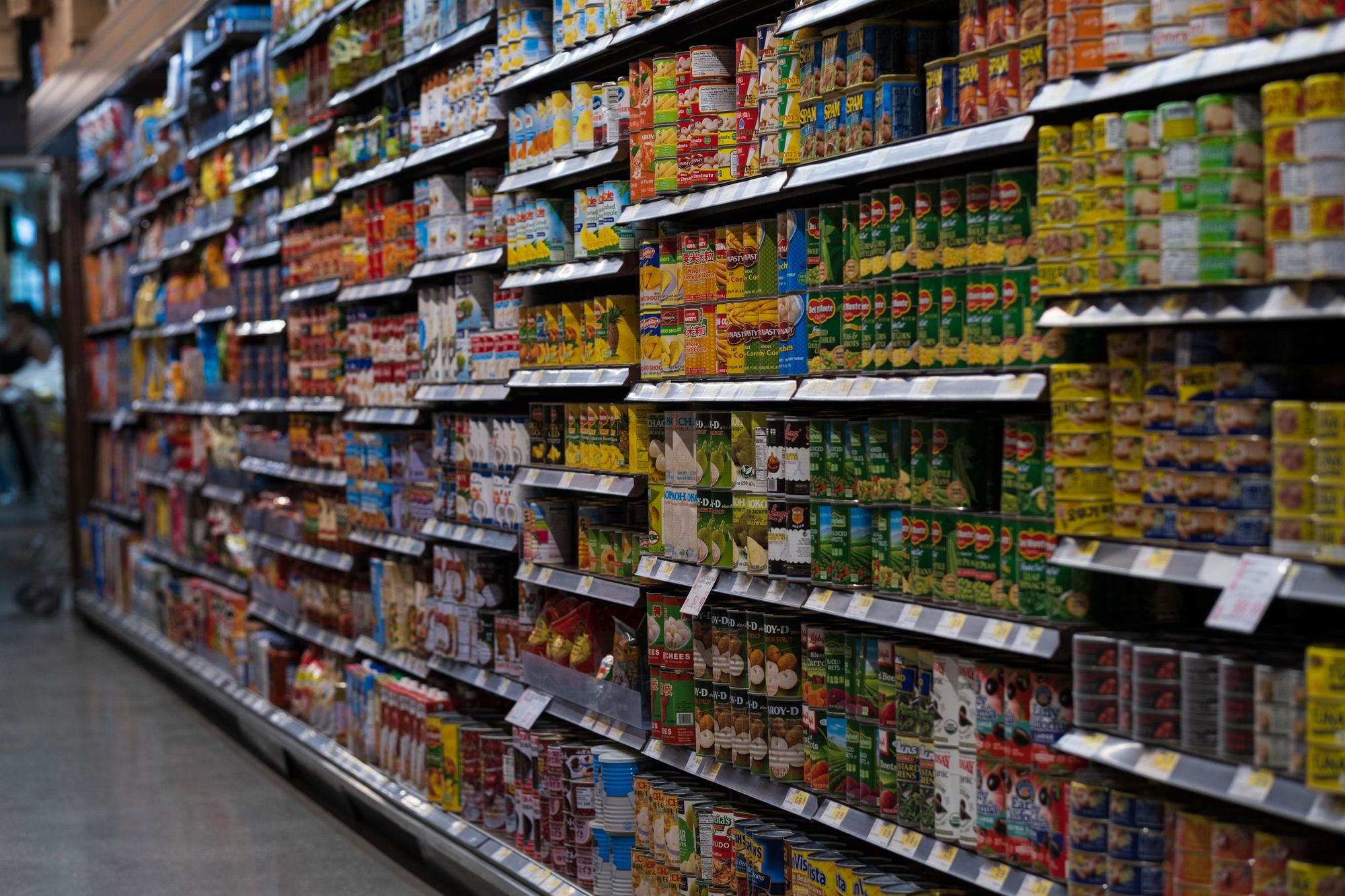 Supermarket aisle shelves stocked with canned goods