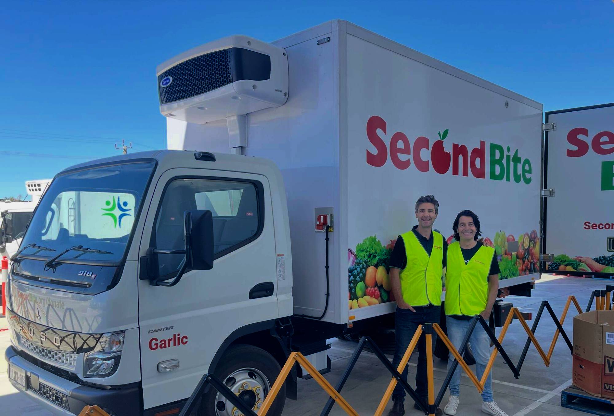 Two men in high-visibility vests beside a refrigerated SecondBite delivery truck