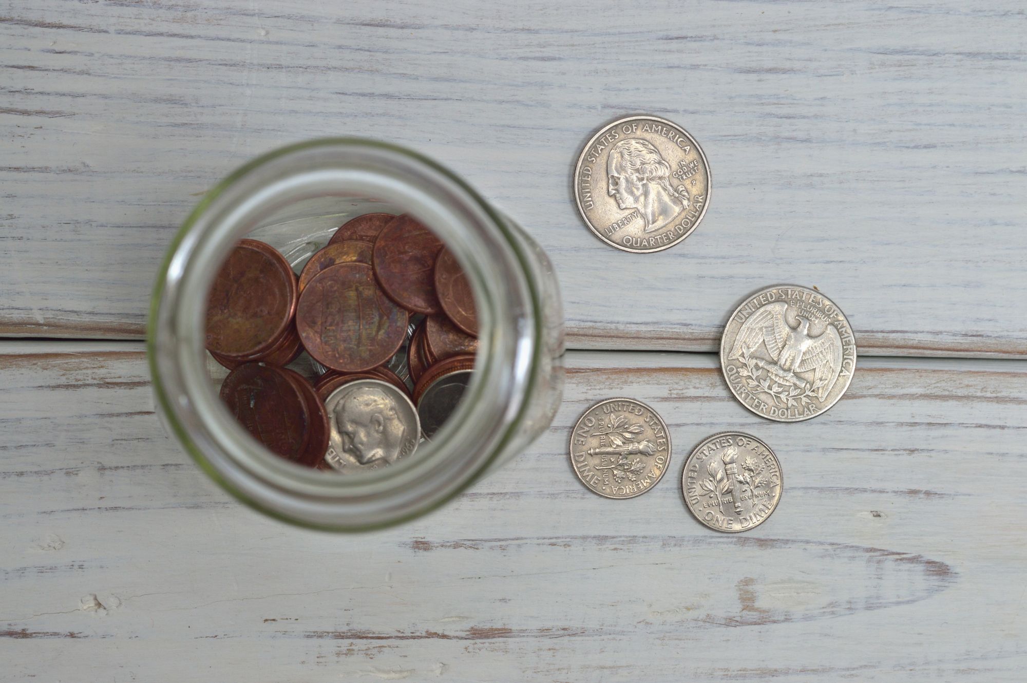 A glass jar filled with coins on a wooden table