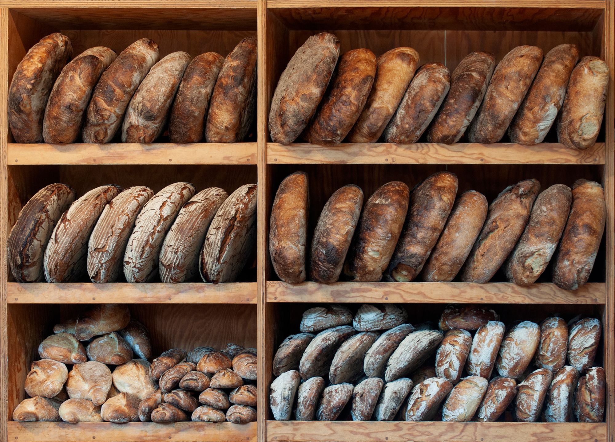 Artisan loaves arranged on wooden bakery shelves