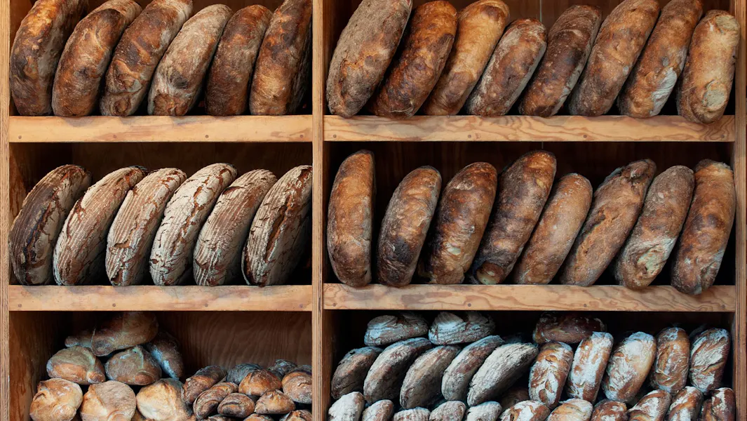 Surplus, not production Artisan loaves arranged on wooden bakery shelves